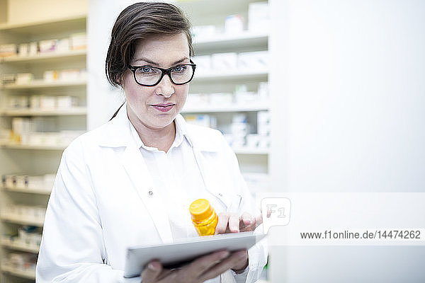 Portrait of pharmacist with tablet and medicine in pharmacy