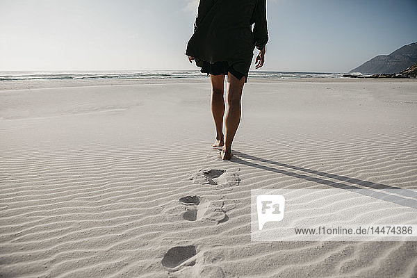 Südafrika  Western Cape  Noordhoek Beach  Rückenansicht einer jungen Frau beim Strandspaziergang