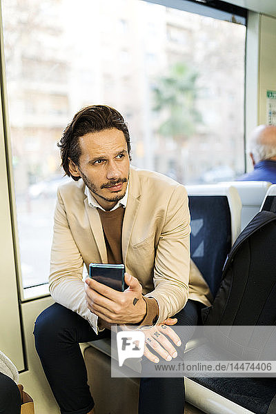 Porträt eines Mannes mit Smartphone in der Strassenbahn