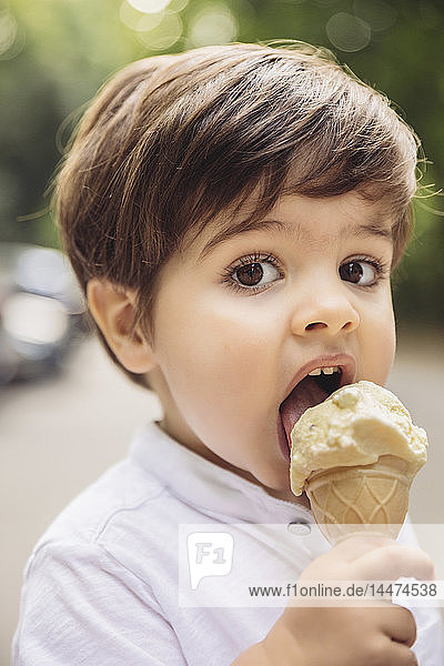 Porträt eines Kleinkindes beim Essen von Vanilleeis im Park
