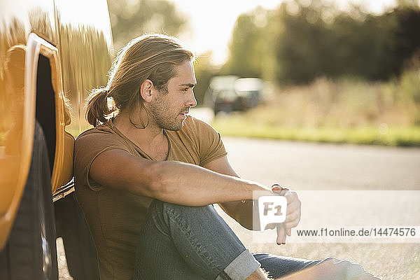 Junger Mann mit seinem Wohnmobil unterwegs  entspannt am Straßenrand