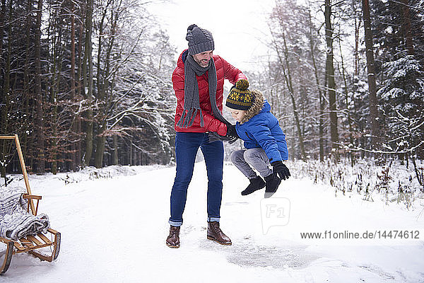 Father and little son having fun together in winter forest