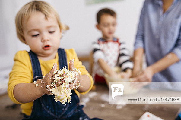 Toddler girl kneading dough with hers hands  close-up