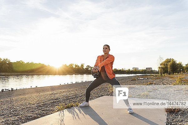 Young woman exercising with a kettlebell at the river