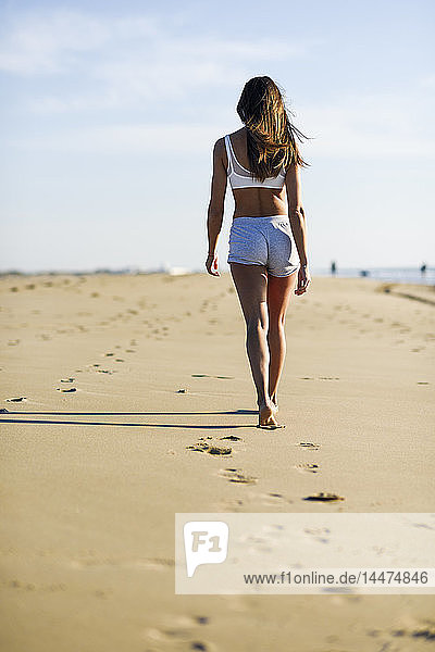 Rückansicht einer Frau  die am Strand im Sand geht
