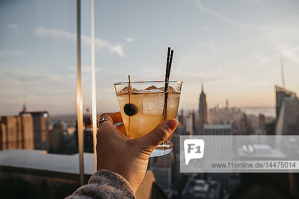 USA  New York  New York City  hand with cocktail glass at sunrise