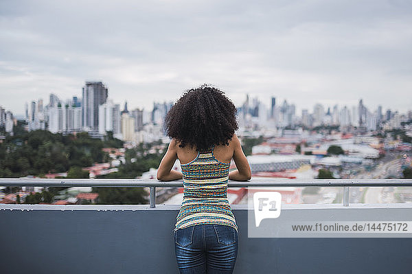 Panama  Panama City  Rückansicht einer jungen Frau  die auf dem Balkon steht und auf die Aussicht schaut