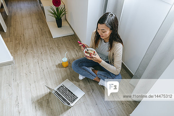Young woman sitting on floor  using smartphone
