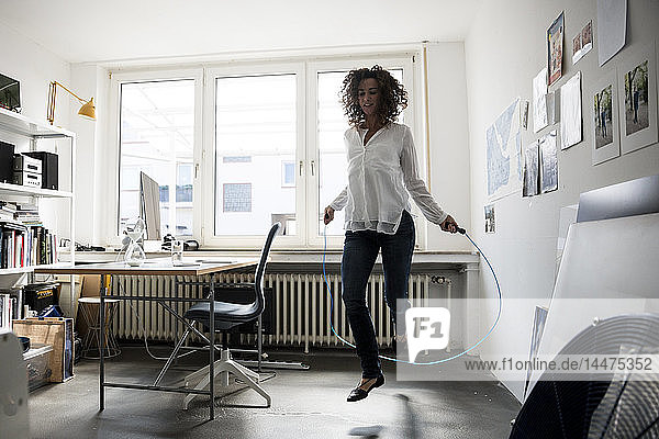 Businesswoman in office  training with skipping rope