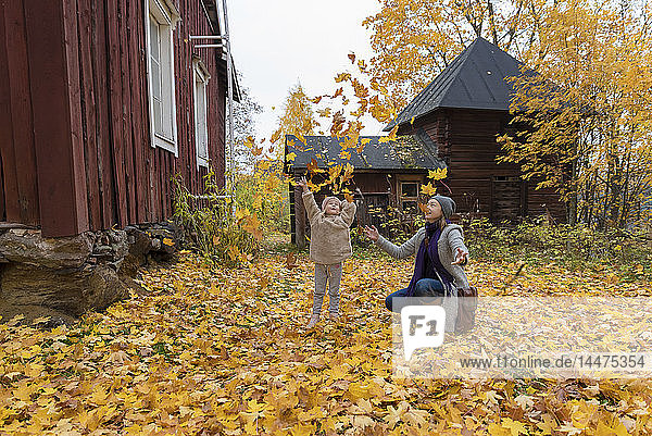 Finnland  Kuopio  Mutter und kleine Tochter werfen Herbstblätter in die Luft