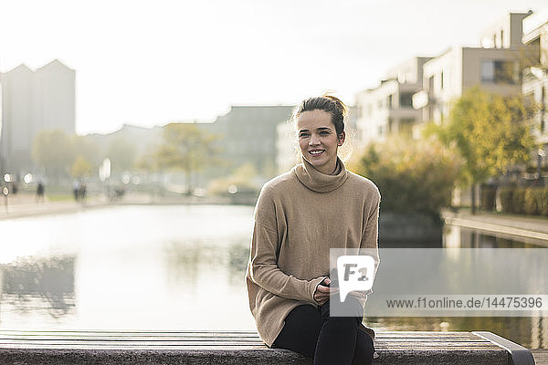 Porträt einer lächelnden Frau mit digitalem Tablett  die im Herbst auf einer Bank sitzt