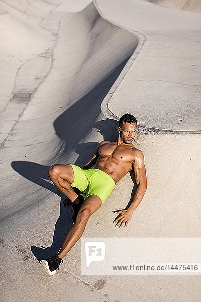 Barechested muscular man posing in a skatepark