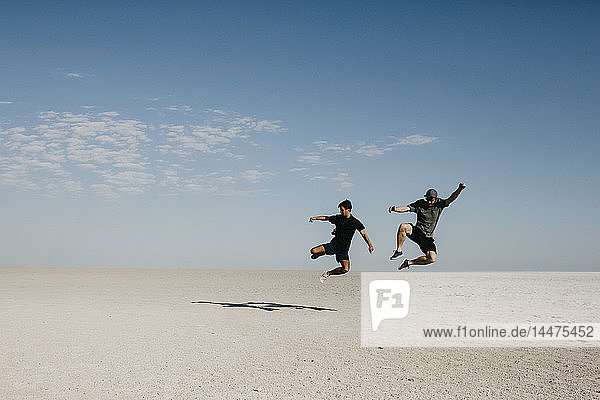 Two young men jumping in te desert