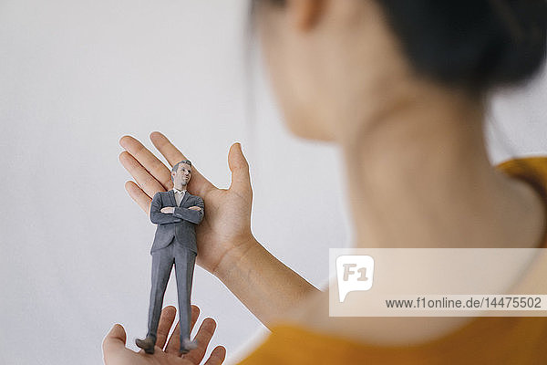 Junge Frau hält Miniatur-Figur ihres Chefs
