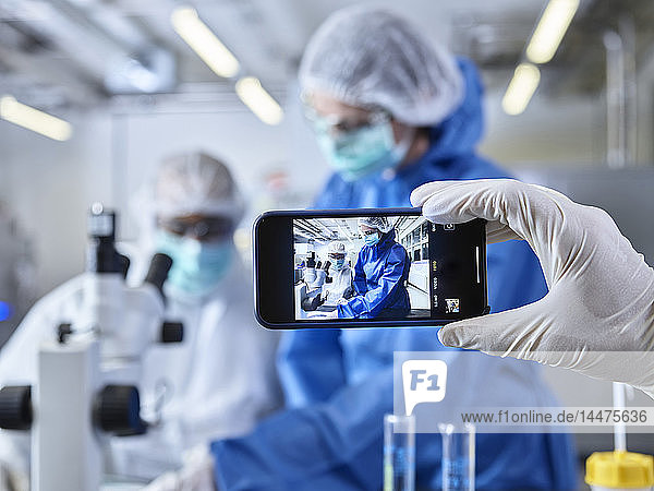 Smartphone in der Hand halten  Chemiker fotografieren  im Industrielabor arbeiten