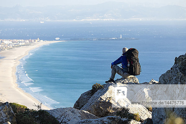Spain Andalusia Tarifa man on a hiking trip at the coast sitting on a rock looking at view