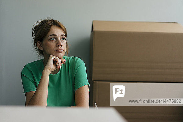 Nachdenkliche Frau neben Pappkartons im Büro