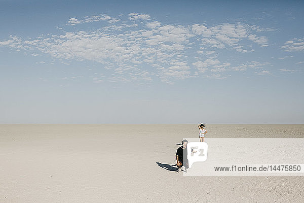 Mann kniet in der Wüste  die Frau scheint auf seiner Hand zu balancieren