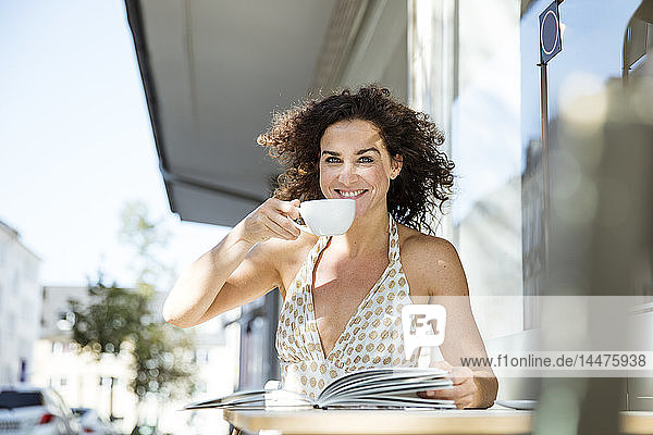 Reife Frau sitzt im Café  liest ein Buch  trinkt Kaffee