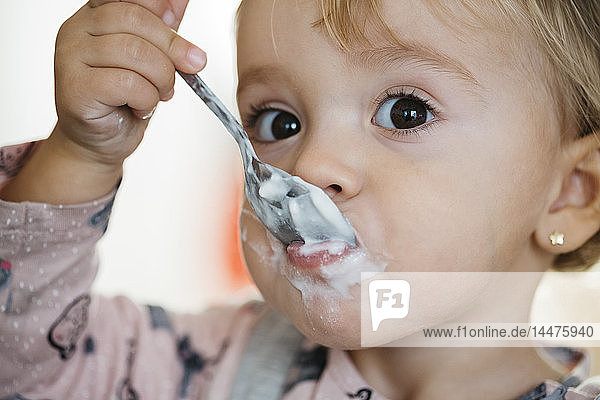 Portrait of baby girl eating yogurt  close-up