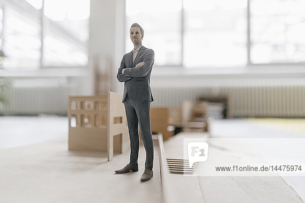 Miniatur-Geschäftsmann-Figur auf Architekturmodell stehend
