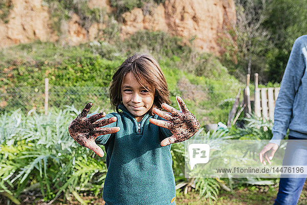 Boy showing his messy hands  full of soil