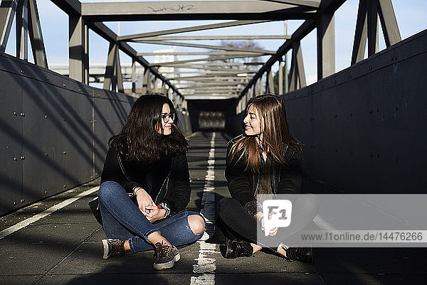 Zwei Freunde sitzen auf einer Brücke und sehen sich an