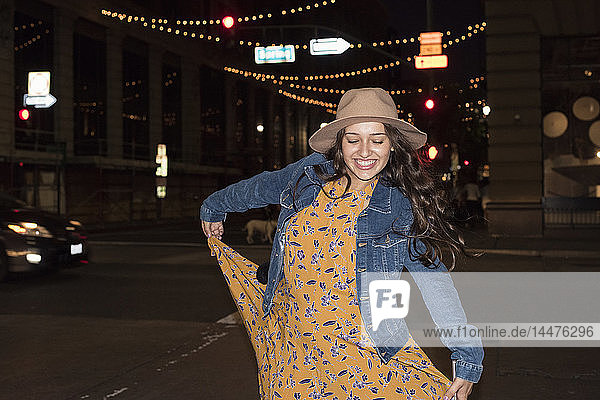 Glückliche junge Frau nachts auf der Straße