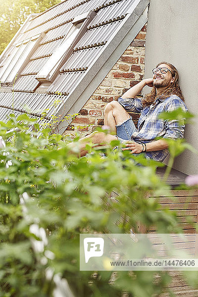 Happy young man sitting on his balcony  relaxing