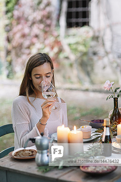 Woman tasting glass of wine at garden table