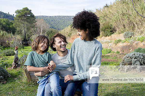 Happy family sitting on a bench in a garden  having fun in the countryside