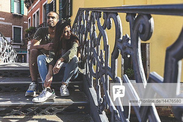 Italien  Venedig  liebevolles junges Paar sitzt auf einer Treppe in der Stadt