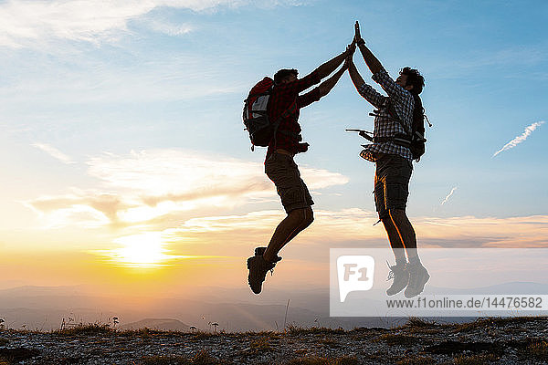 Italien  Monte Nerone  zwei glückliche und erfolgreiche Wanderer  die bei Sonnenuntergang in den Bergen springen