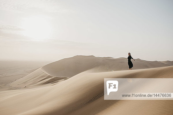 Namibia  Namib  schwarz gekleidete Frau auf Wüstendüne stehend