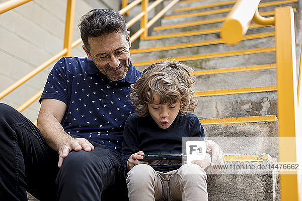 Vater beobachtet Sohn beim Spielen mit tragbarer Spielkonsole