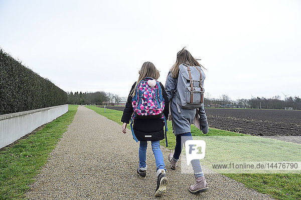 Two sisters with backpacks walking side by side
