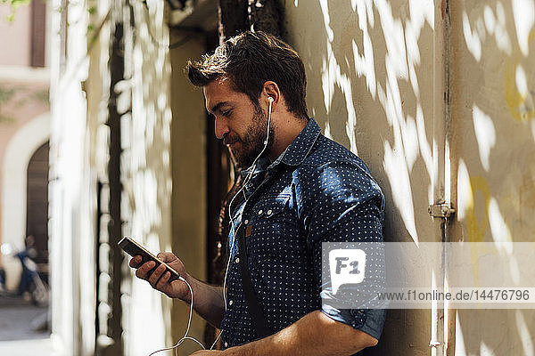 Mann benutzt Kopfhörer und Smartphones im Freien