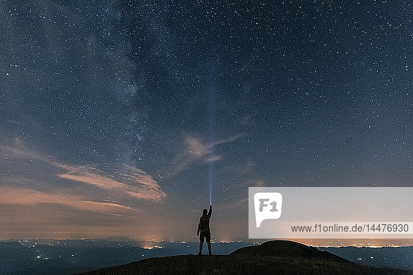 Italien  Monte Nerone  Silhouette eines Mannes mit Fackel unter Nachthimmel mit Sternen und Milchstraße