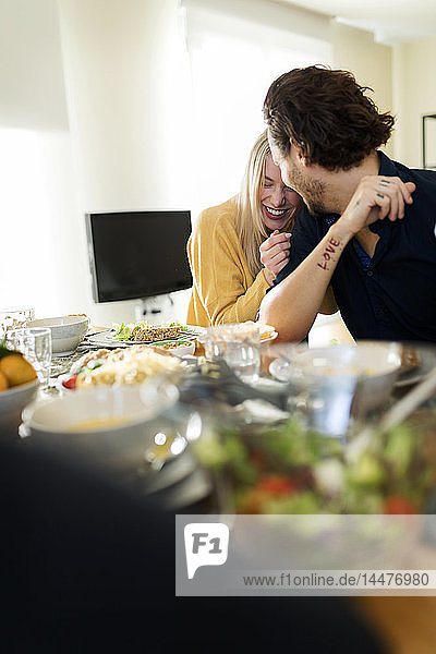 Freunde beim gemeinsamen Mittagessen  liebevolles Paar küsst sich am Tisch