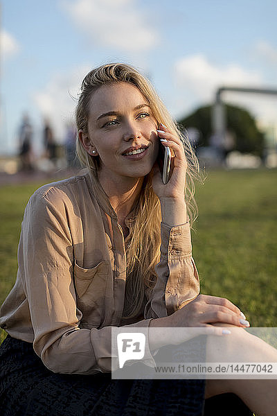 Smiling young businesswoman on cell phone on a meadow