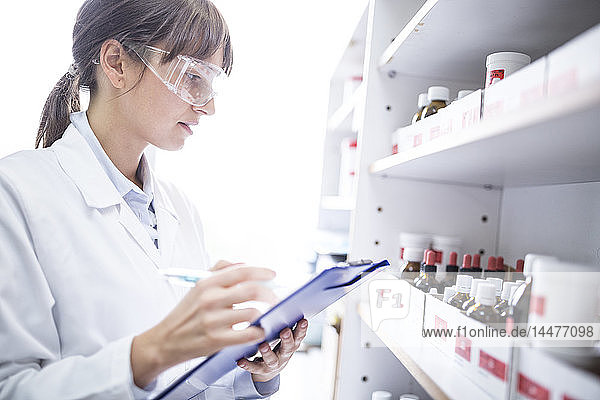 Woman holding clipboard in laboratory of a pharmacy