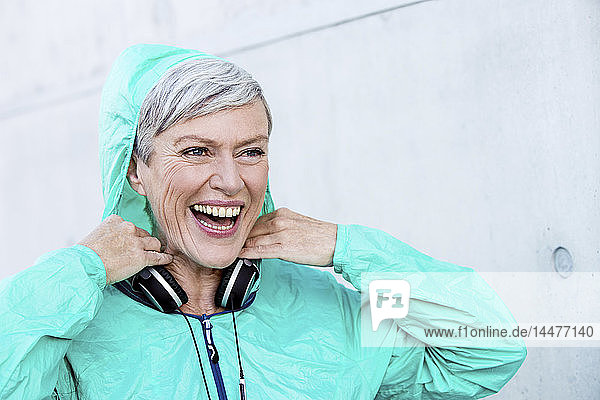 Porträt einer lachenden  sportlichen  reifen Frau mit Kopfhörern