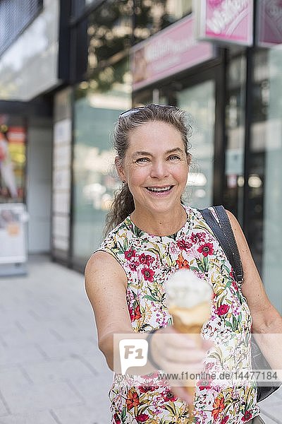 Portrait of smiling mature woman with ice cream cone in the city