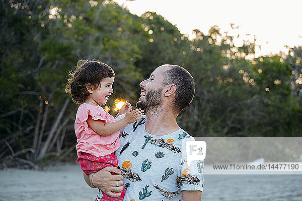 Australien  Queensland  Mackay  Cape Hillsborough National Park  glücklicher Vater hält seine Tochter bei Sonnenuntergang am Strand