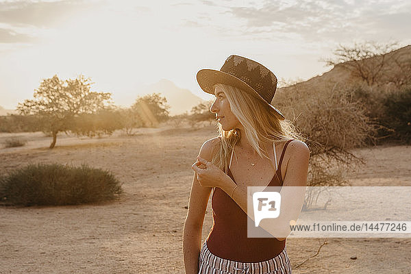Namibia  Spitzkoppe  Frau mit Hut bei Sonnenuntergang