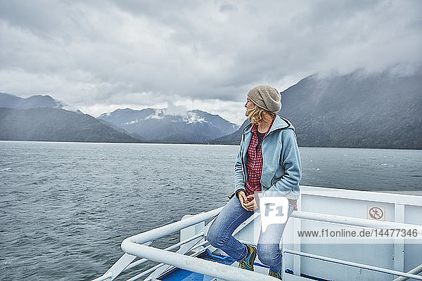 Chile  Hornopiren  Frau sitzt auf der Reling einer Fähre und schaut auf den Fjord
