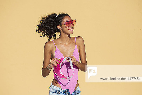 Porträt einer Teenagerin mit Sonnenbrille  orange Wand