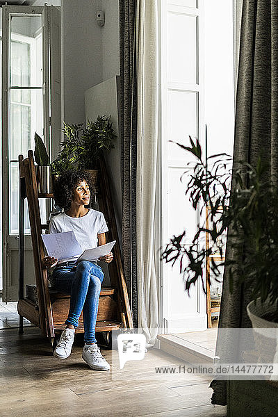 Frau sitzt zu Hause auf Stufen mit Dokument