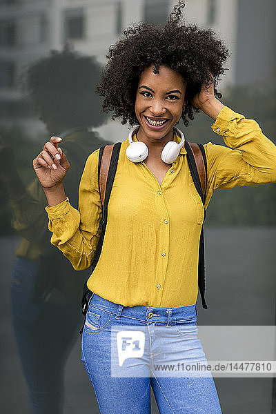 Porträt einer lachenden Frau mit Rucksack und Kopfhörer