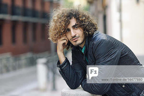 Portrait of smiling young man with beard and curly hair outdoors